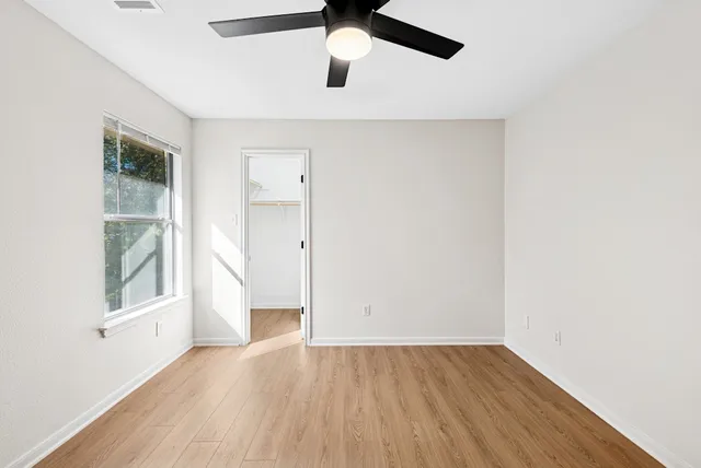 a view of empty room with wooden floor and fan