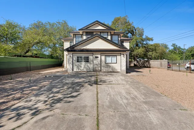 a front view of a house with a dirt yard and a large tree