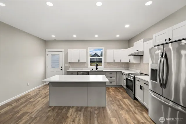 a large kitchen with stainless steel appliances a sink and cabinets
