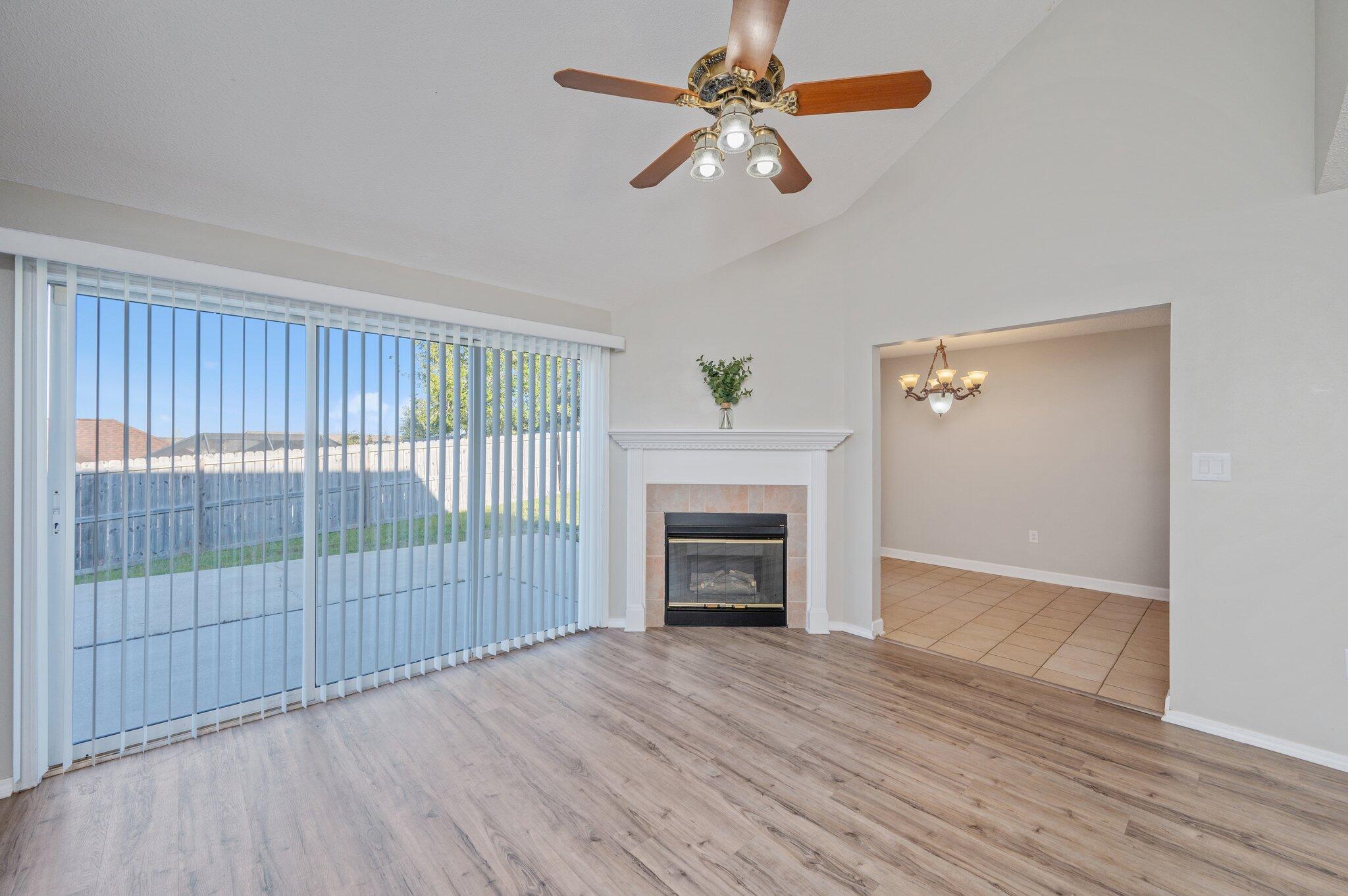 903 Twain Lane Crestview, FL 32536 - Photo 9 of 58 an empty room with wooden floor a ceiling fan and a fireplace