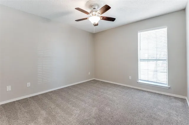 an empty room with a window and a fan