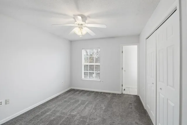 an empty room with windows and fan