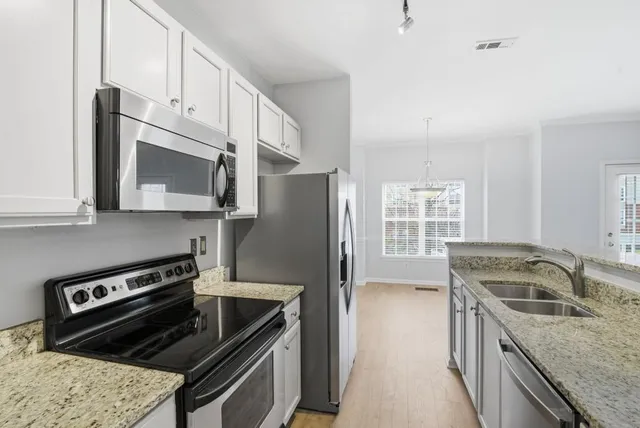 a kitchen with granite countertop a refrigerator stove and microwave