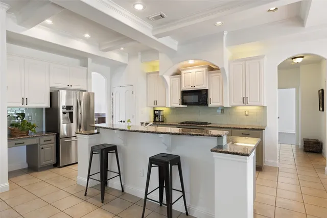 a kitchen with stainless steel appliances granite countertop a stove top oven a sink a dining table and chairs