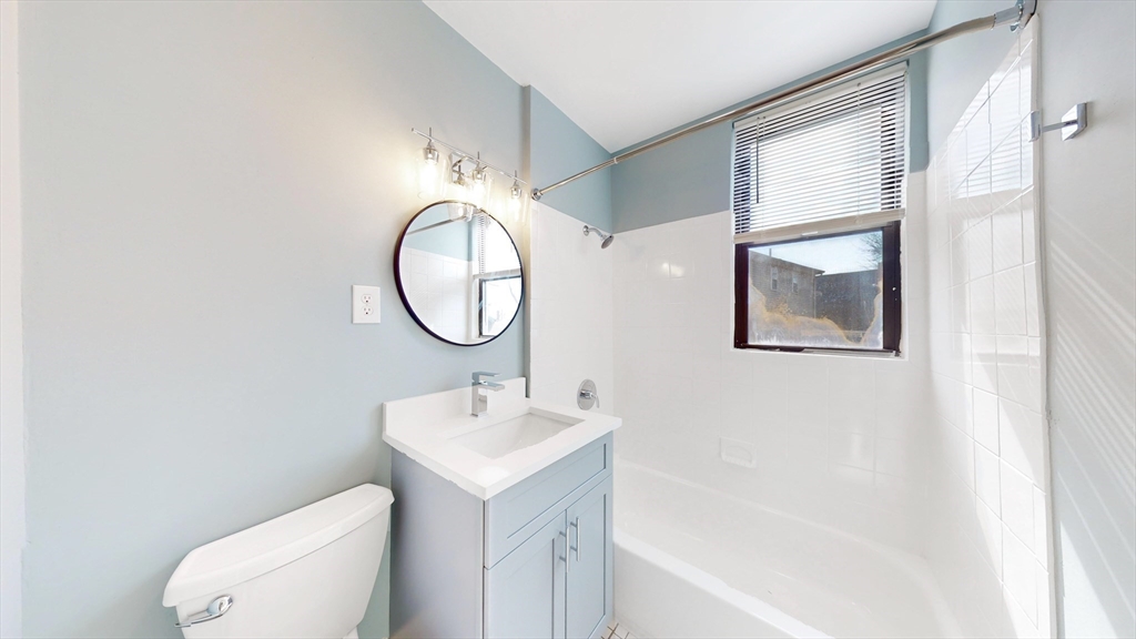 181 Highland Street, Unit 1 Boston, MA 02119 - Photo 6 of 11 a bathroom with a sink mirror and toilet