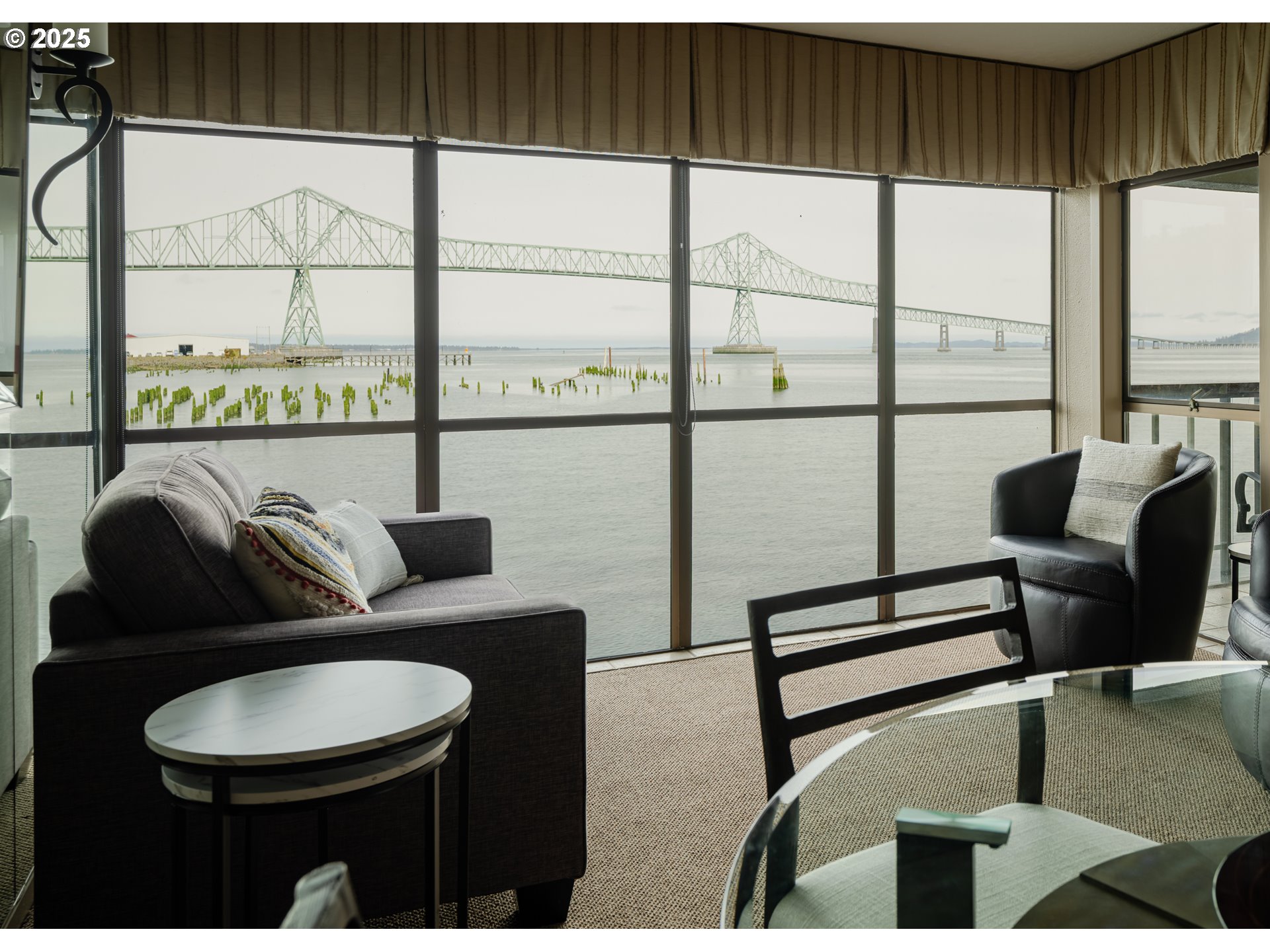 1 3rd Street, Unit 209 Astoria, OR 97103 - Photo 25 of 37 a living room with furniture floor to ceiling window and a flat screen tv