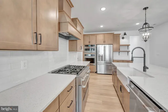 a kitchen with stainless steel appliances granite countertop a sink stove a refrigerator and cabinets with wooden floor