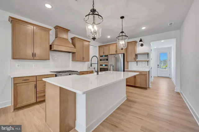a kitchen with stainless steel appliances granite countertop a sink a stove and a wooden floors