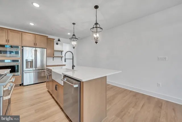 a kitchen with kitchen island a sink stainless steel appliances and refrigerator