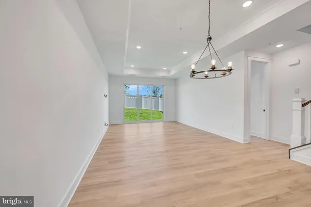 a view of empty room with wooden floor and kitchen