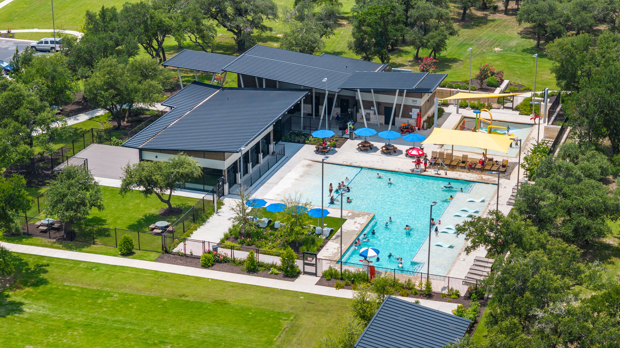 313 Mclintock Road Jarrell, TX 76537 - Photo 37 of 40 An aerial perspective showcases a vibrant community pool area, complete with a modern building and abundant green spaces.