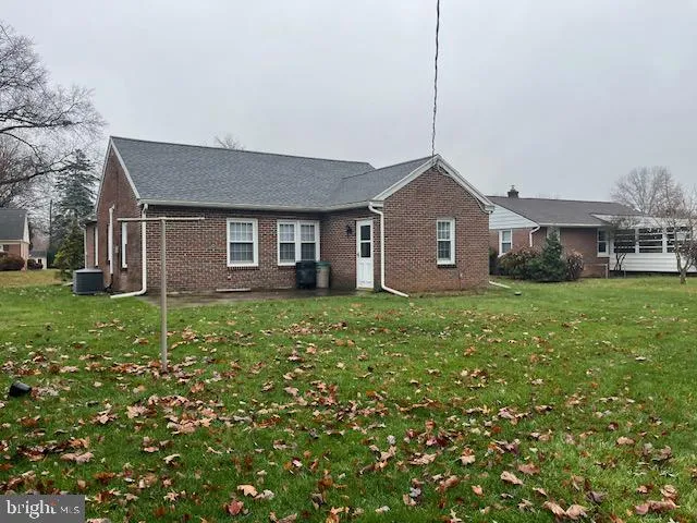 a brick house with a big yard and large trees