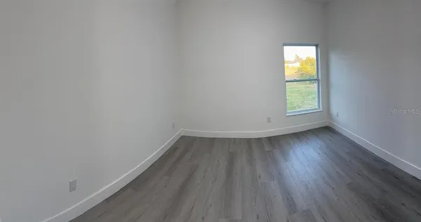 an empty room with a window and wooden floor