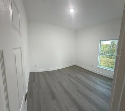 an empty room with wooden floor and window