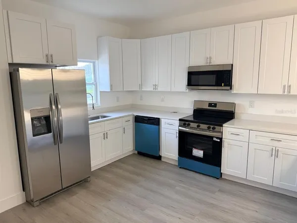 a kitchen with stainless steel appliances granite countertop a refrigerator a stove a sink and white cabinets