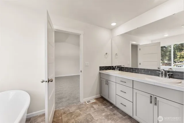 a spacious bathroom with a double vanity sink a mirror and a bathtub