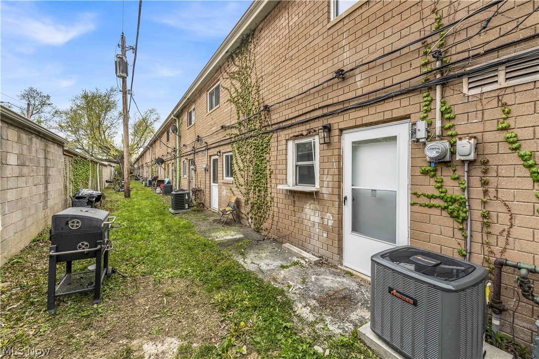 797 Babbitt Road, Unit 15 Euclid, OH 44123 - Photo 20 of 22 Rear exterior featuring brick construction, climbing greenery, individual outdoor units, and multiple entry points