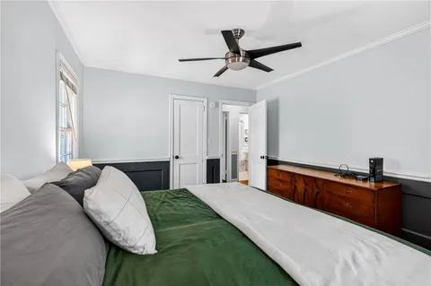 a bedroom with a large bed and a chandelier fan