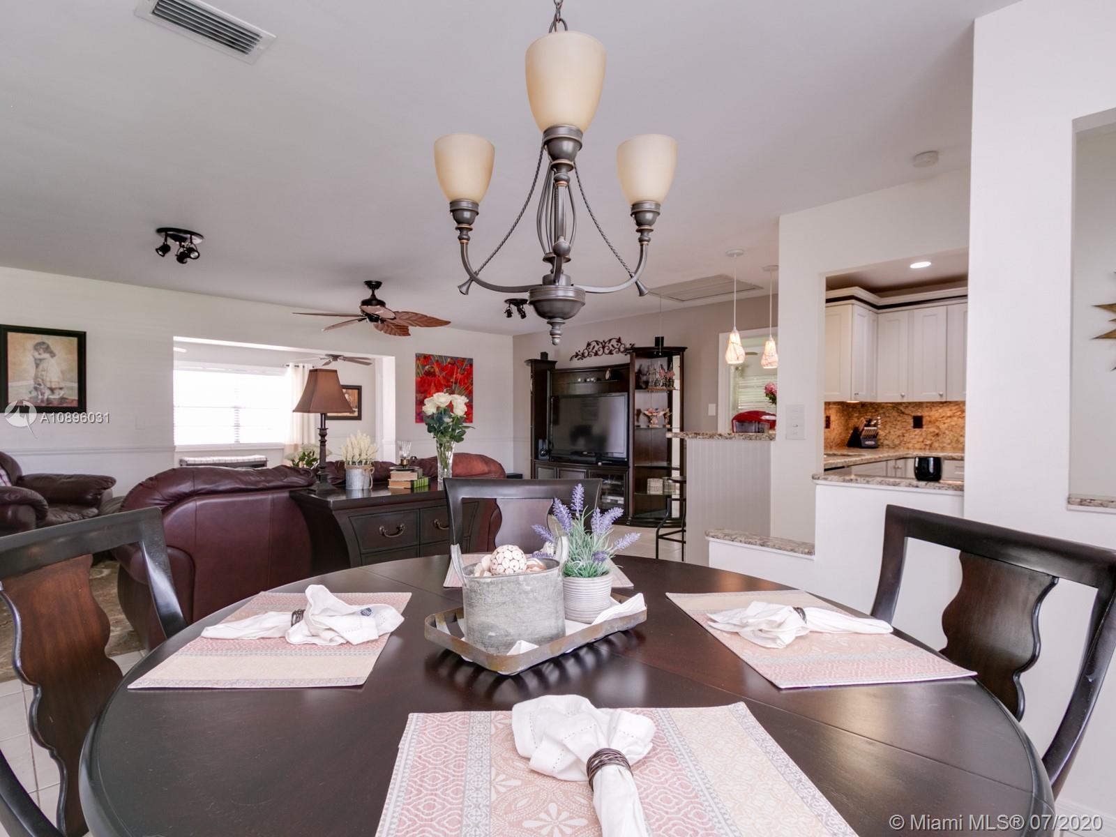 9518 Burlington Place Boca Raton, FL 33434 - Photo 12 of 35 a living room with furniture a chandelier and a dining table