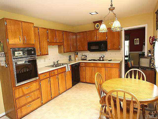 4308 Union Street Raleigh, NC 27609 - Photo 4 of 8 a kitchen with stainless steel appliances a sink a stove a refrigerator cabinets and a dining table with chairs