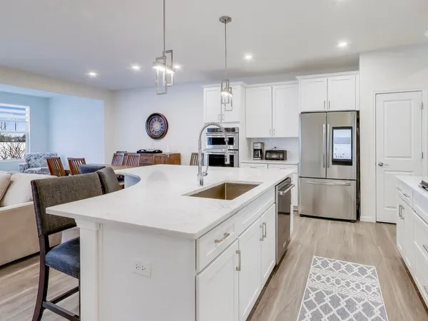 a kitchen with stainless steel appliances a refrigerator a sink a stove and chairs
