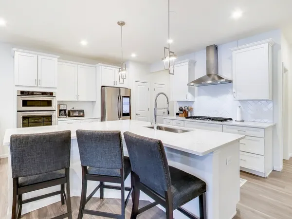 a kitchen with a dining table chairs stainless steel appliances and cabinets