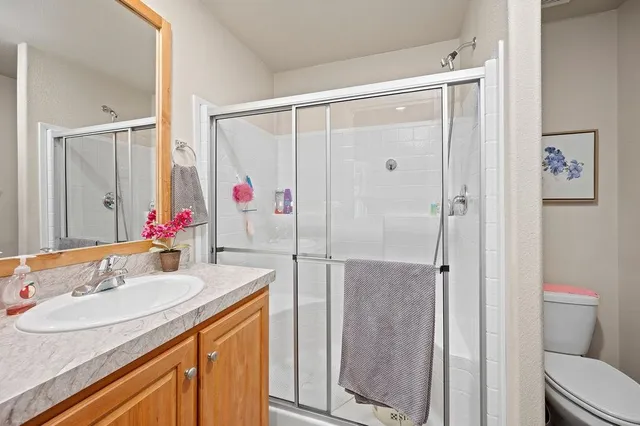 a bathroom with a granite countertop shower sink vanity and toilet