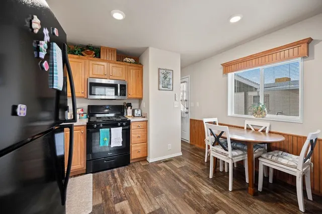 a kitchen with granite countertop a stove top oven a sink dishwasher a dining table and chairs with wooden floor