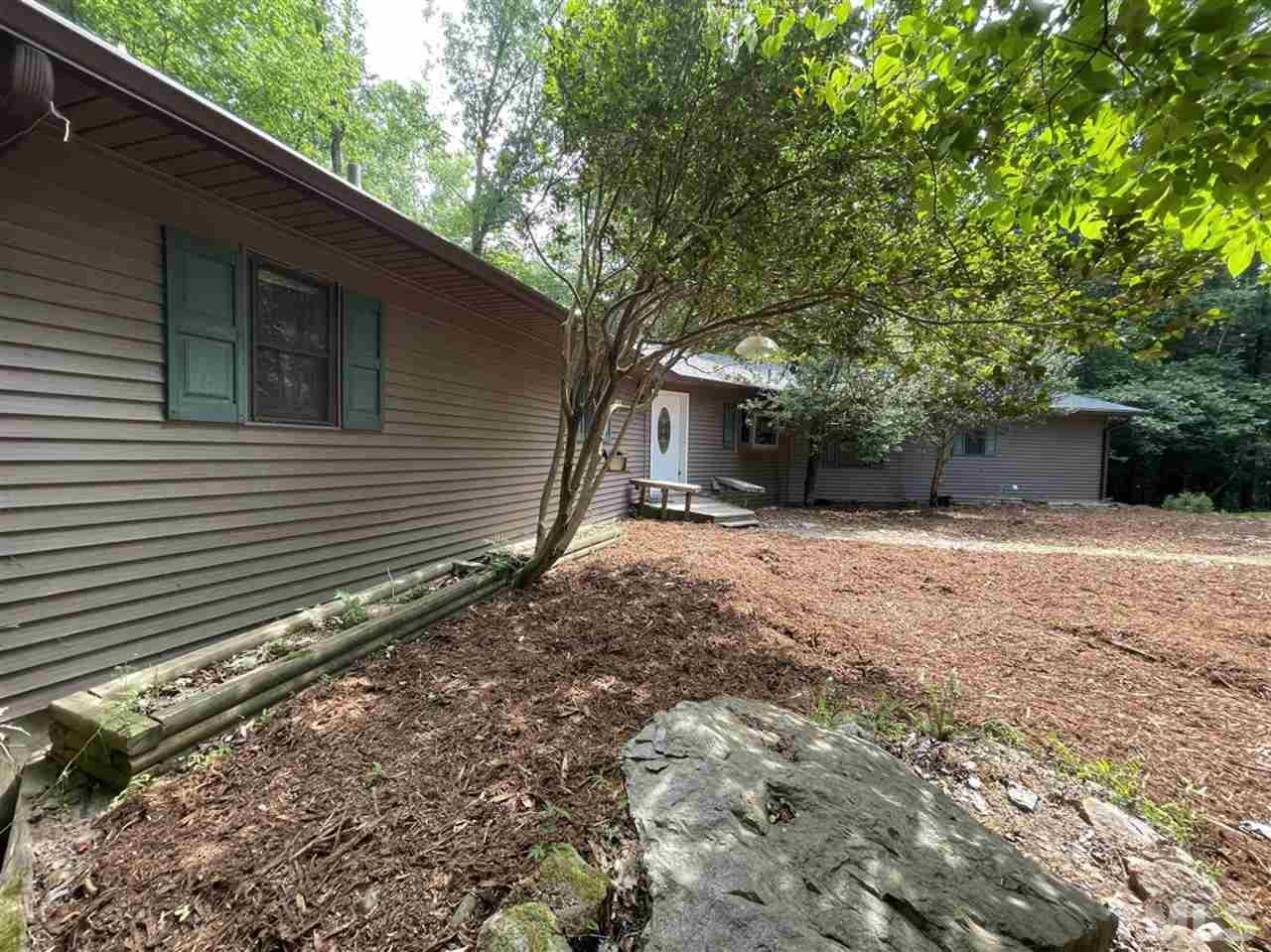 371 Lassiter Road Pittsboro, NC 27312 - Photo 4 of 19 a backyard of a house with large trees and brick walls