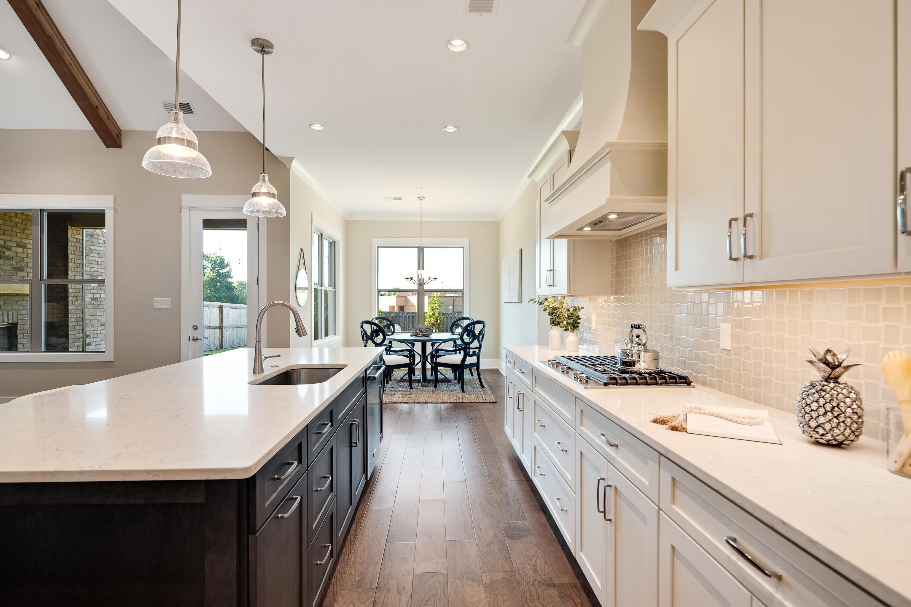 10136 Cliveden Circle North Collierville, TN 38017 - Photo 15 of 39 Kitchen featuring appliances with stainless steel finishes, custom range hood, dark wood-type flooring, tasteful backsplash, and hanging light fixtures