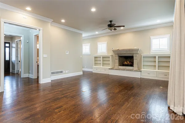 an empty room with wooden floor fireplace and windows