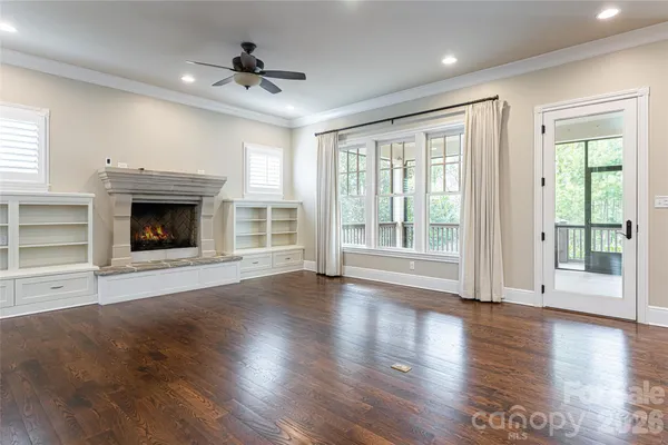 a view of an empty room with wooden floor fireplace and a window