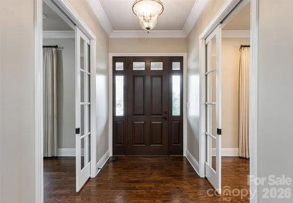 a view of a hallway with wooden floor and a chandelier