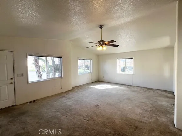 an empty room with a chandelier fan and windows