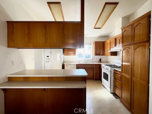 a kitchen with stainless steel appliances a sink a stove a refrigerator a sink a counter top space and cabinets