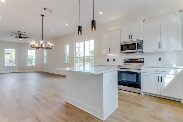 a kitchen with kitchen island white cabinets and stainless steel appliances