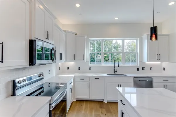 a kitchen that has a sink a stove and a wooden floor