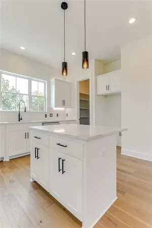 a kitchen with stainless steel appliances granite countertop a sink a window and white cabinets