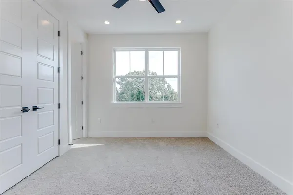 an empty room with chandelier fan and windows