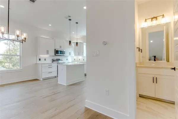 a view of a kitchen with white cabinets and wooden floor