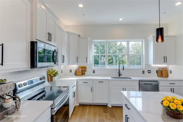 a kitchen that has a sink and a stove with wooden floor