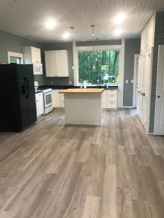 a large kitchen with stainless steel appliances a large counter top a refrigerator and cabinets