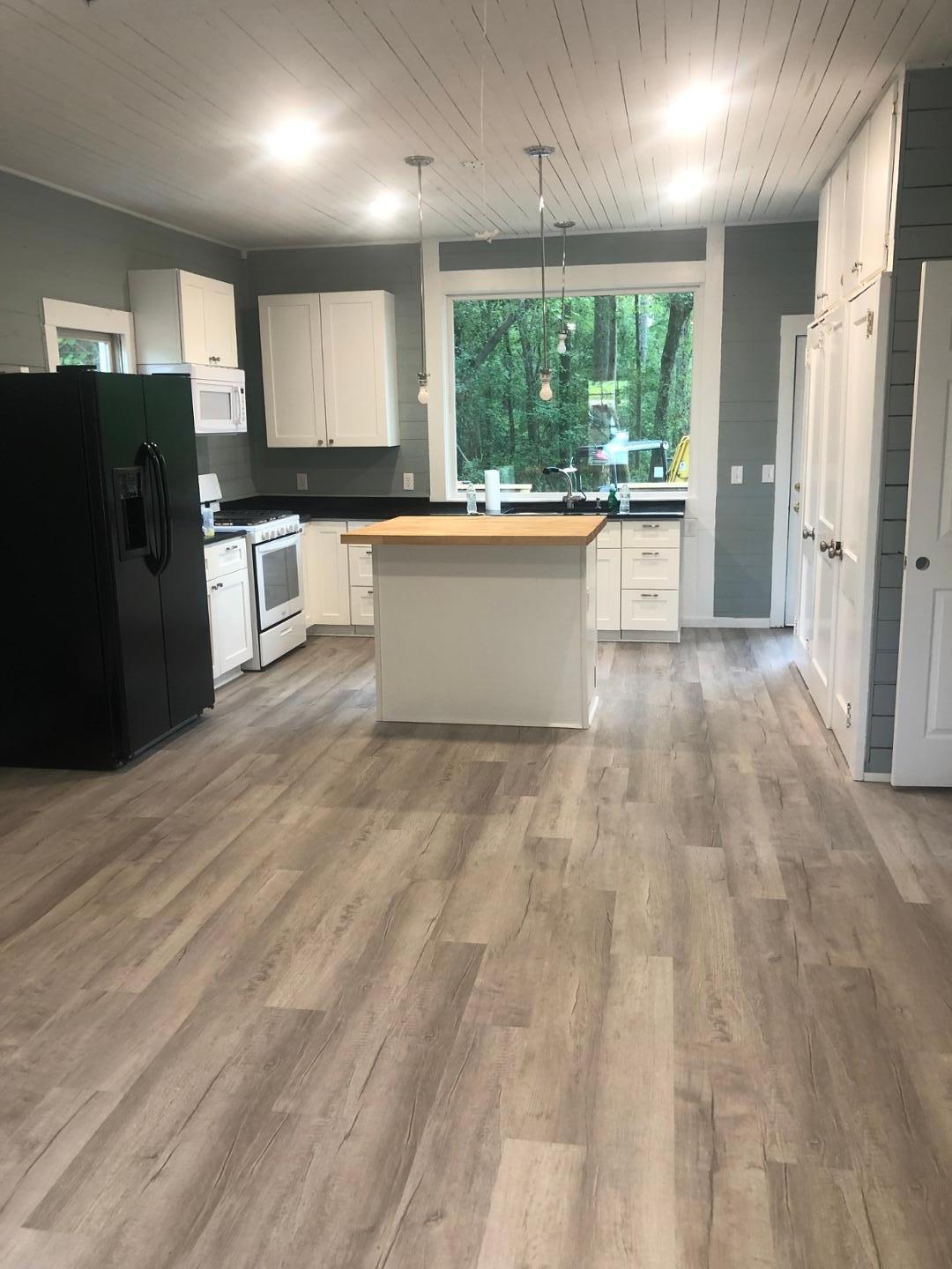 a large kitchen with stainless steel appliances a large counter top a refrigerator and cabinets