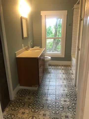 a bathroom with a sink toilet and large mirror