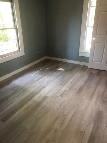 an empty room with wooden floor and windows
