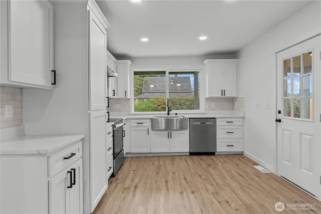 a kitchen with a lot of white cabinets and wooden floor