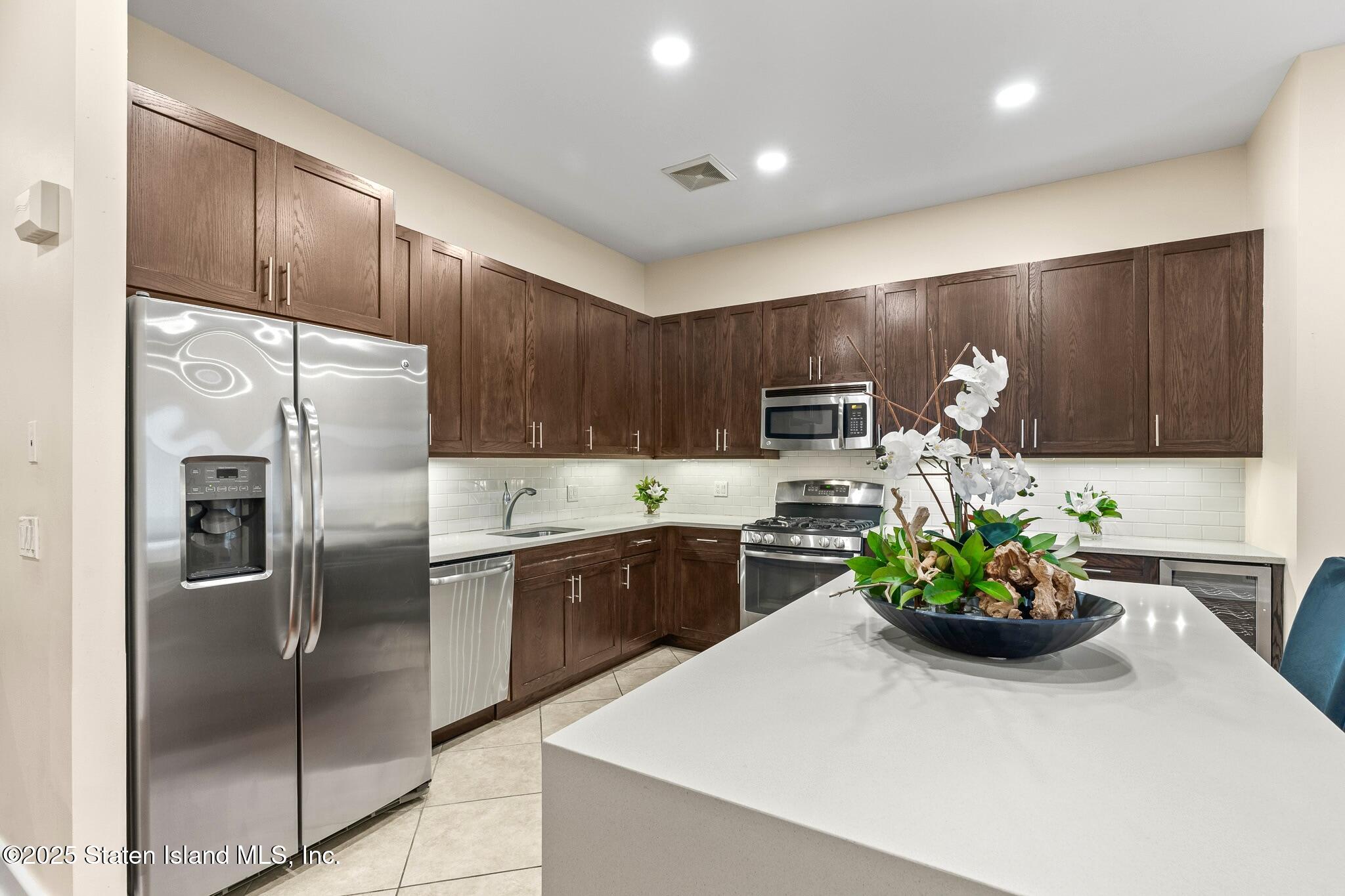 90 Bay Street Landing, Unit 1F Staten Island, NY 10301 - Photo 13 of 55 a kitchen with stainless steel appliances a refrigerator sink and wooden cabinets