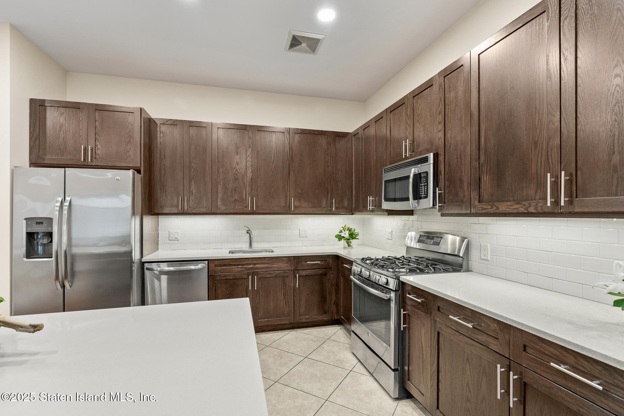 90 Bay Street Landing, Unit 1F Staten Island, NY 10301 - Photo 21 of 55 a kitchen with stainless steel appliances granite countertop a sink stove microwave refrigerator and cabinets