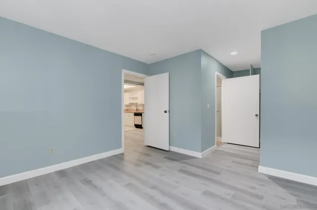 a view of an empty room with wooden floor and closet