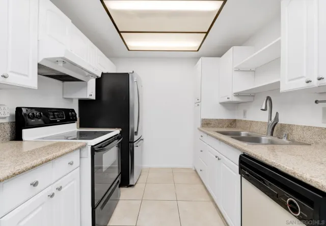 a kitchen with granite countertop a sink a stove and refrigerator